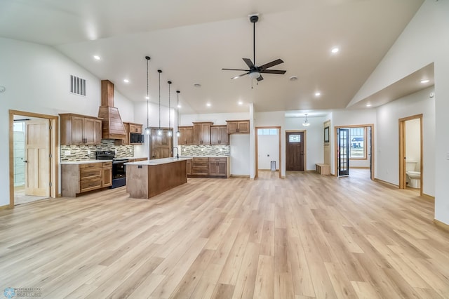 kitchen featuring electric range oven, a kitchen island, high vaulted ceiling, and light hardwood / wood-style flooring