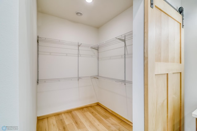 spacious closet with a barn door and hardwood / wood-style floors