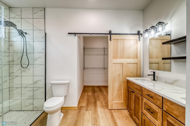 bathroom with toilet, vanity, wood-type flooring, and tiled shower