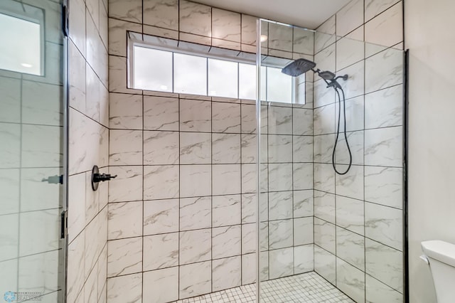 bathroom featuring a shower with door, toilet, and plenty of natural light