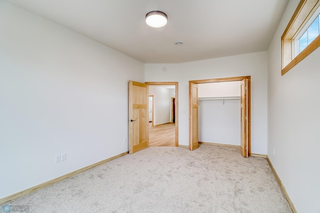 unfurnished bedroom featuring light carpet and a closet