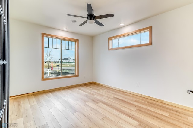 empty room with ceiling fan, a wealth of natural light, and light hardwood / wood-style flooring