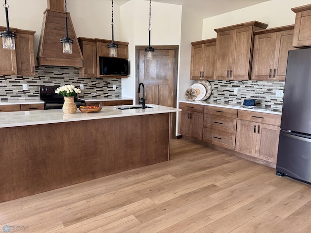 kitchen featuring a sink, light countertops, decorative backsplash, custom range hood, and black appliances