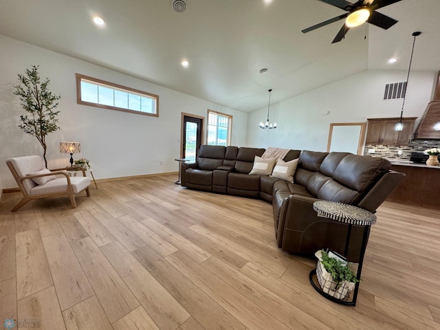 living area featuring high vaulted ceiling, light wood-style flooring, ceiling fan with notable chandelier, recessed lighting, and visible vents