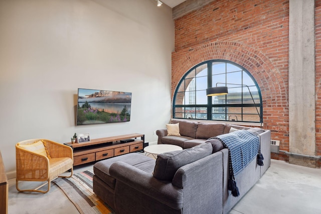 living room with a towering ceiling and brick wall