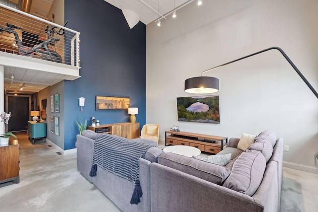 living room with concrete floors, rail lighting, and a high ceiling