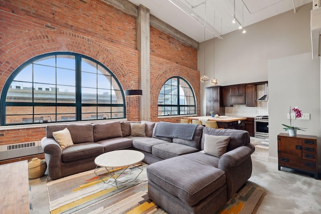 living room with brick wall, rail lighting, and a high ceiling