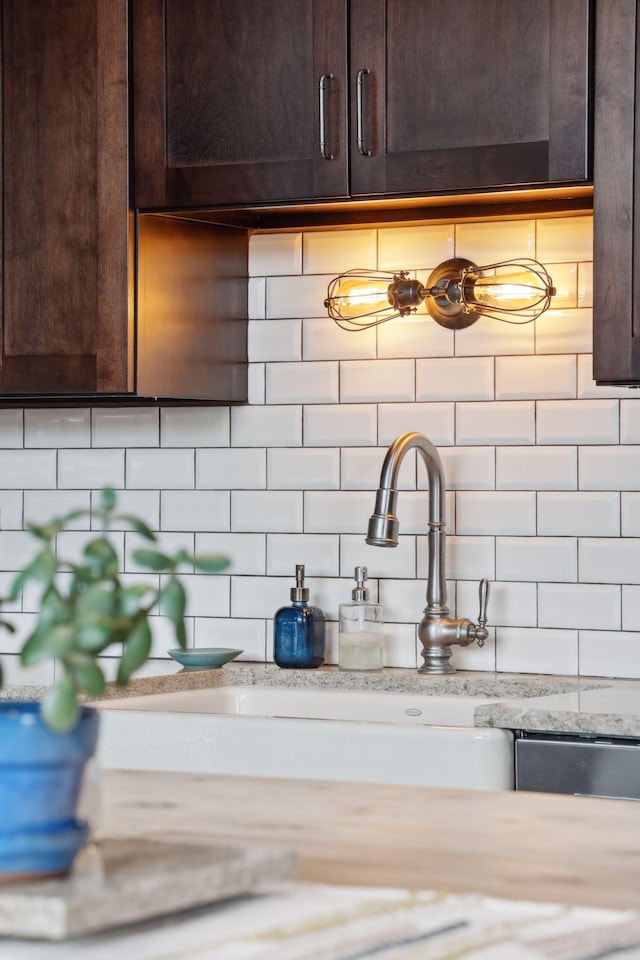 details with light stone countertops, backsplash, and dark brown cabinetry