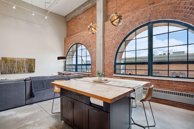 interior space featuring wood counters, brick wall, radiator, and a kitchen island