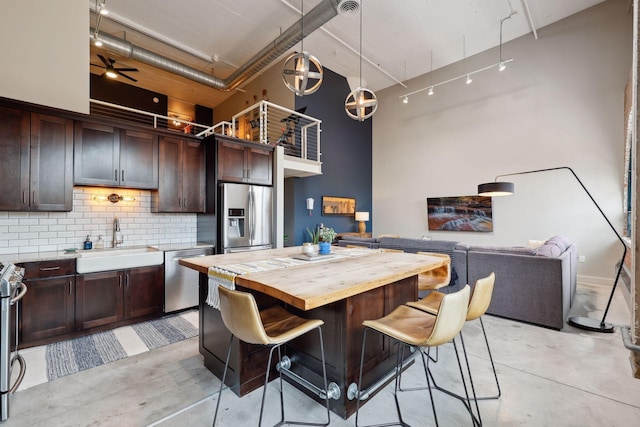 kitchen with stainless steel appliances, a high ceiling, sink, and pendant lighting