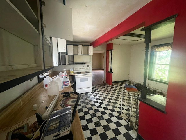 kitchen with white electric range, white cabinetry, and tile patterned flooring