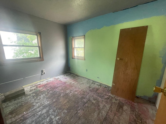 unfurnished room with a textured ceiling and wood-type flooring