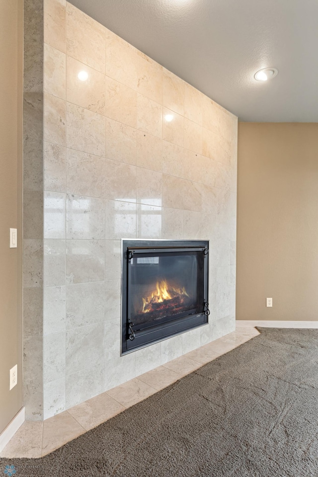 interior details with a tile fireplace and carpet