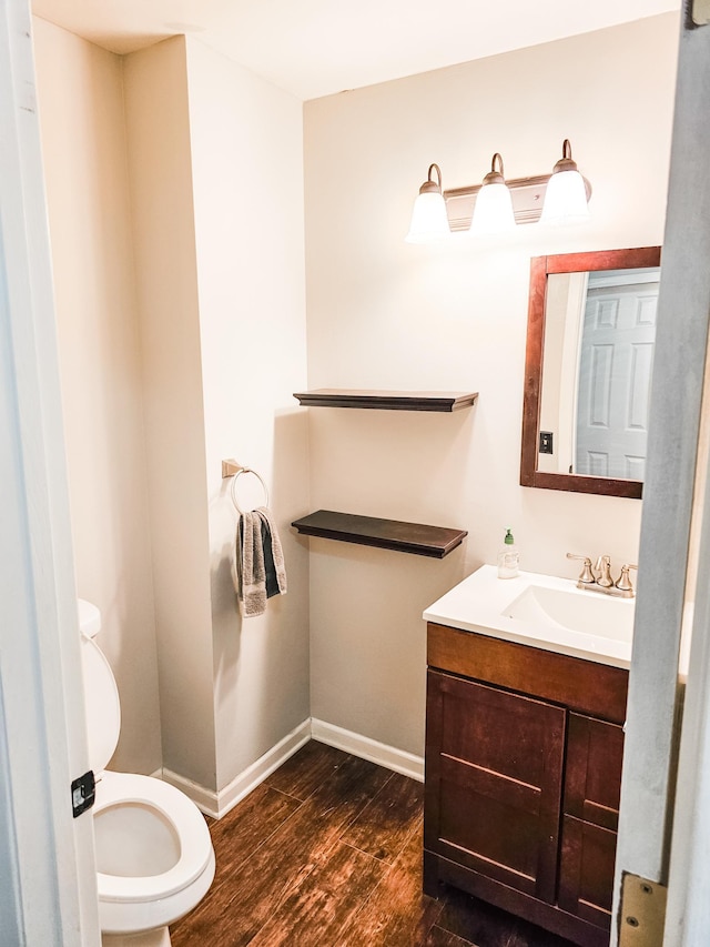 bathroom with hardwood / wood-style floors, vanity, and toilet