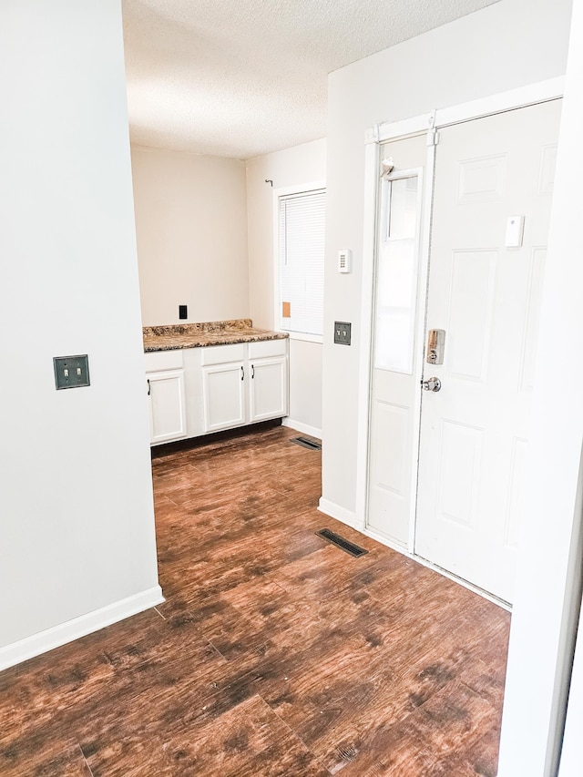 kitchen featuring stone counters, white cabinetry, dark hardwood / wood-style floors, and a textured ceiling