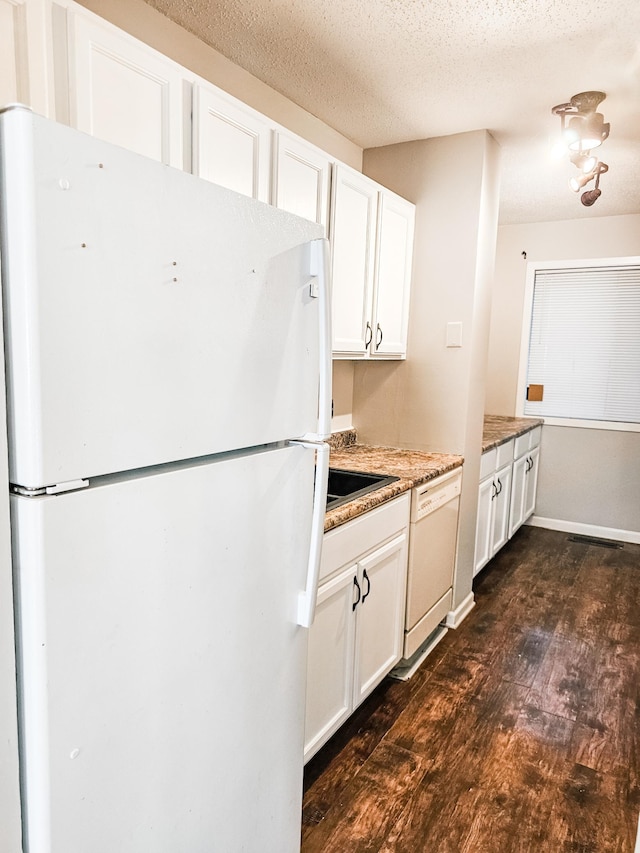 kitchen featuring a textured ceiling, white cabinets, dark wood-type flooring, and white appliances