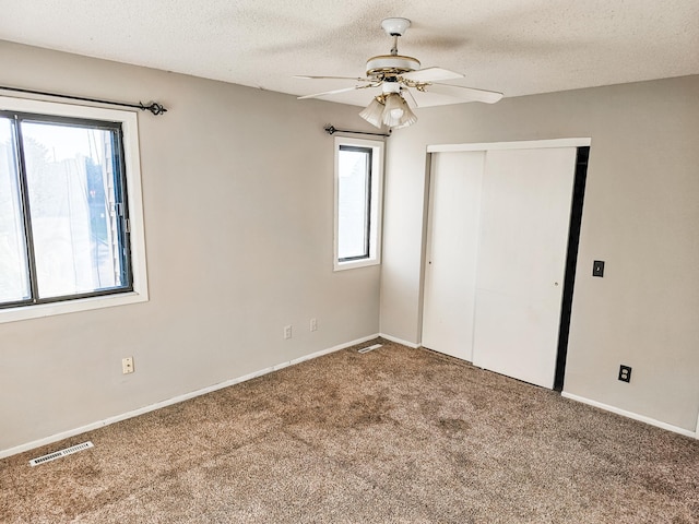 unfurnished bedroom with carpet flooring, ceiling fan, a closet, and a textured ceiling