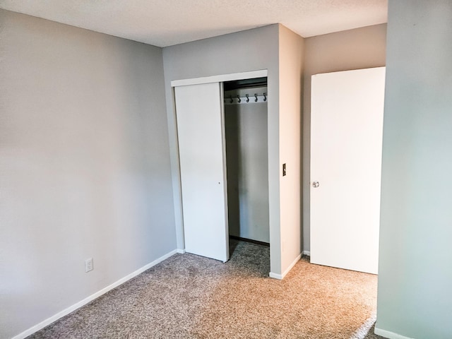 unfurnished bedroom with carpet, a textured ceiling, and a closet