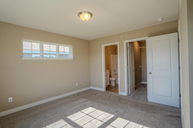 unfurnished bedroom with carpet flooring, a walk in closet, a closet, and connected bathroom