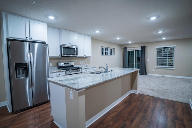 kitchen featuring a textured ceiling, stainless steel appliances, a kitchen island with sink, sink, and white cabinetry