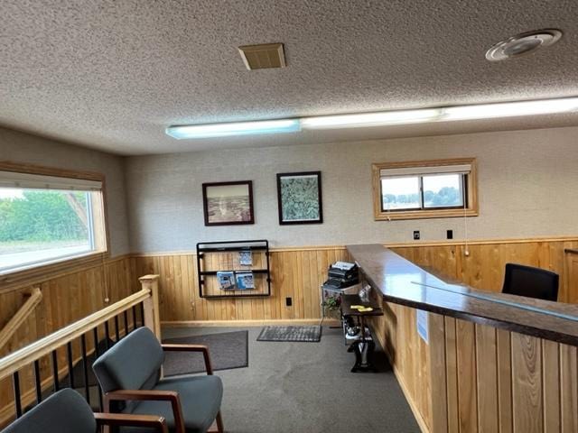 office area with wooden walls, a textured ceiling, and carpet flooring