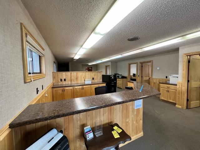 kitchen featuring dark carpet, kitchen peninsula, a textured ceiling, and a kitchen bar