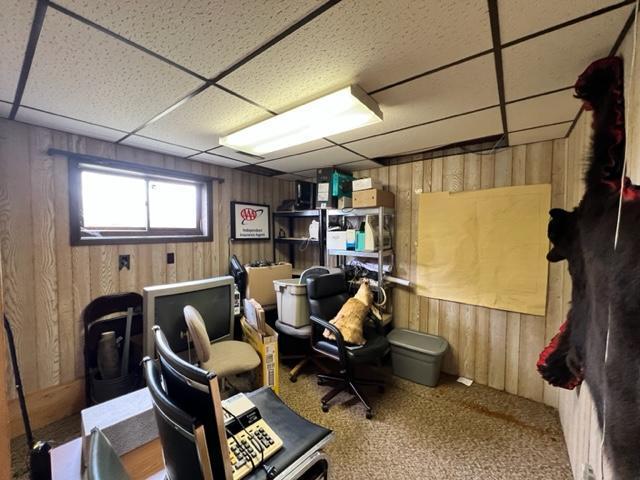 interior space with a paneled ceiling and wooden walls