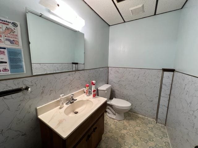 bathroom with vanity, tile walls, and toilet