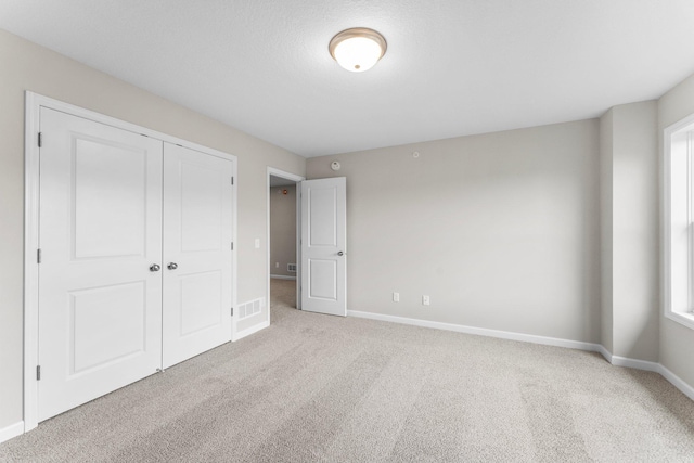 unfurnished bedroom with light carpet and a closet