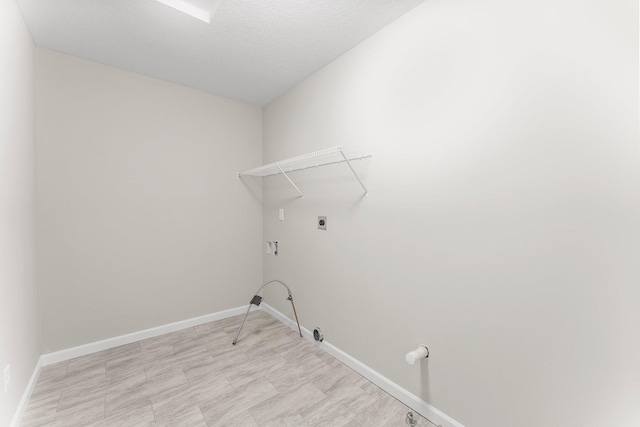 clothes washing area with a textured ceiling, light tile patterned flooring, gas dryer hookup, and hookup for an electric dryer