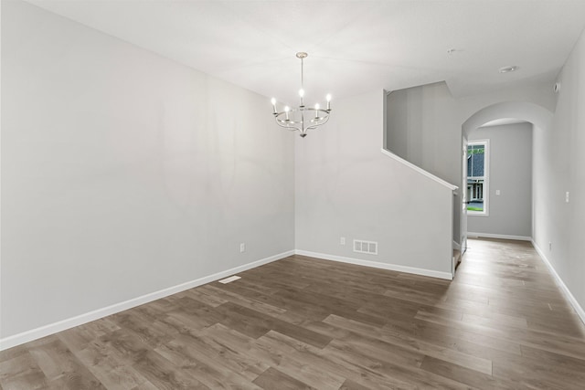 unfurnished room featuring hardwood / wood-style flooring and a chandelier