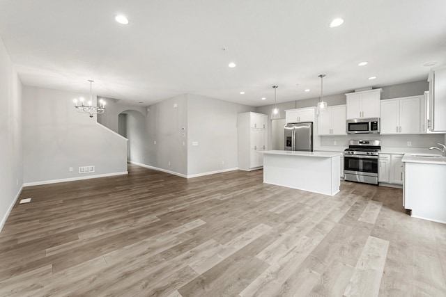 kitchen featuring a notable chandelier, a center island, stainless steel appliances, sink, and light wood-type flooring