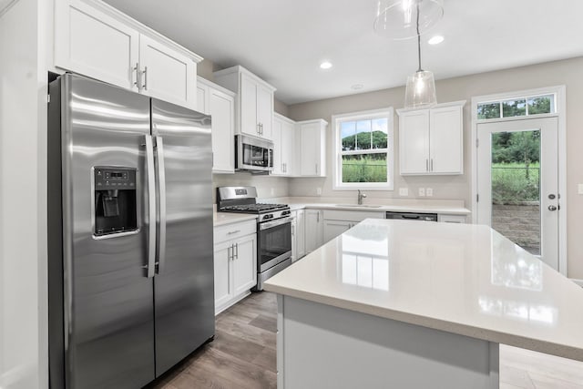 kitchen with a kitchen island, appliances with stainless steel finishes, sink, light wood-type flooring, and white cabinets