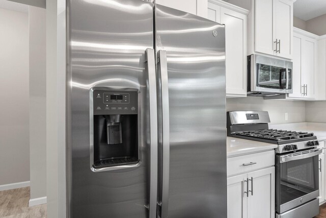 kitchen featuring stainless steel appliances, light wood-type flooring, and white cabinetry