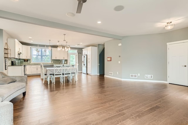 living room featuring ceiling fan with notable chandelier and hardwood / wood-style floors