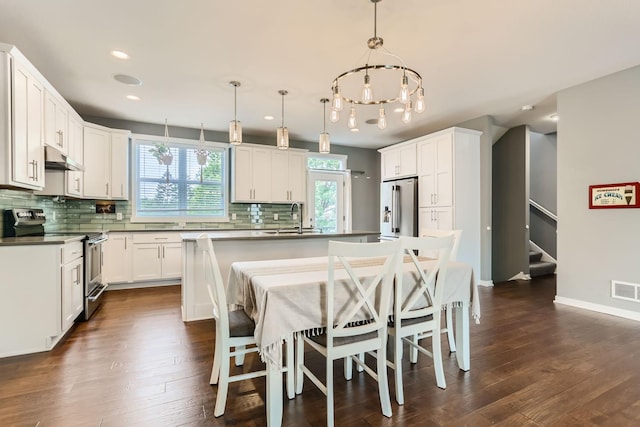 kitchen with appliances with stainless steel finishes, backsplash, dark hardwood / wood-style floors, and a kitchen island