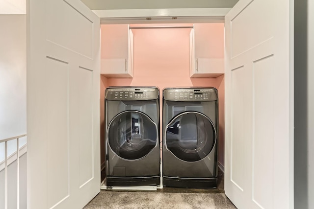 clothes washing area with washer and dryer, light carpet, and cabinets