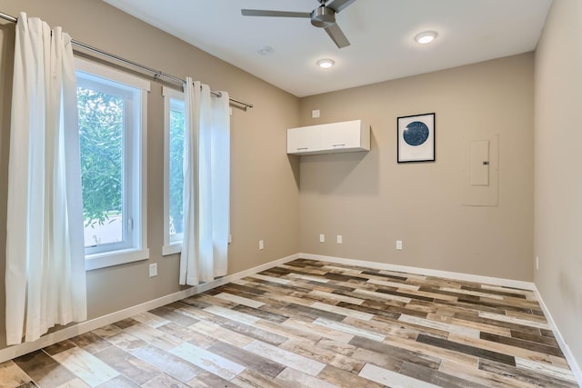 empty room featuring light hardwood / wood-style floors, electric panel, and ceiling fan