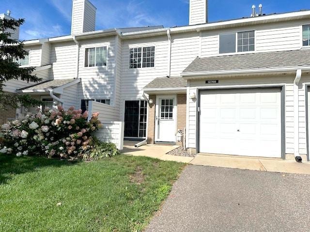 multi unit property featuring a front yard and a garage