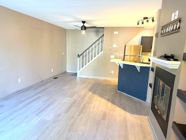 living room with light hardwood / wood-style flooring, track lighting, and ceiling fan