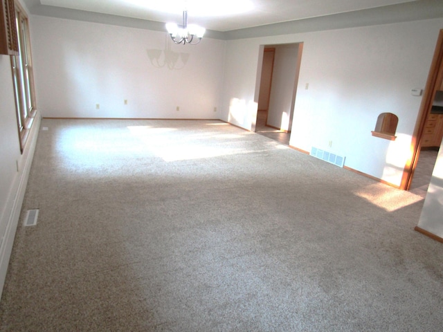 spare room with a chandelier and light colored carpet