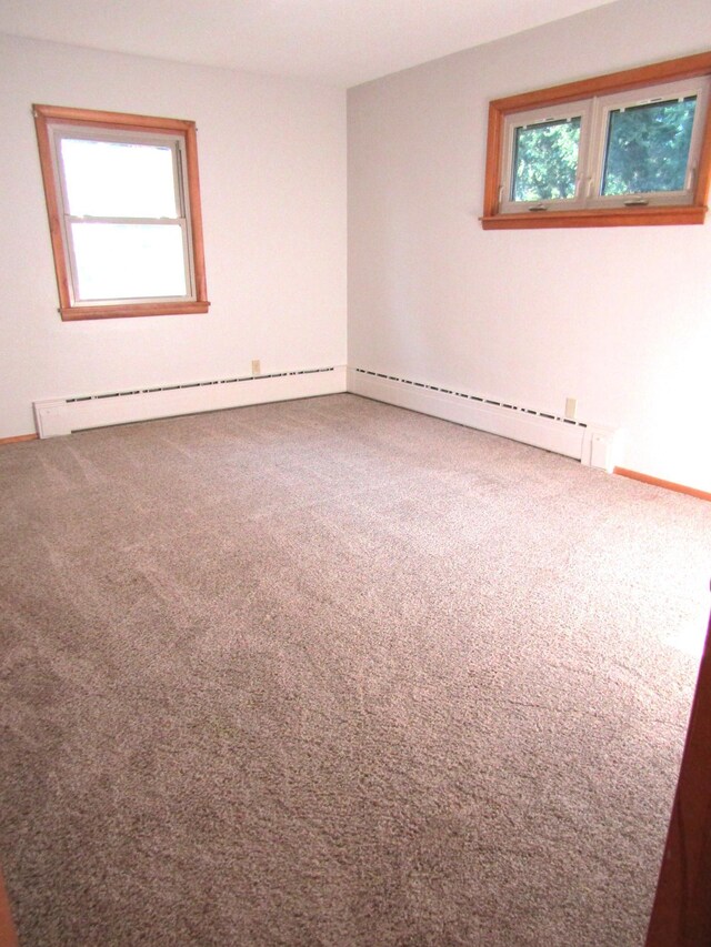 unfurnished room with a baseboard heating unit and carpet