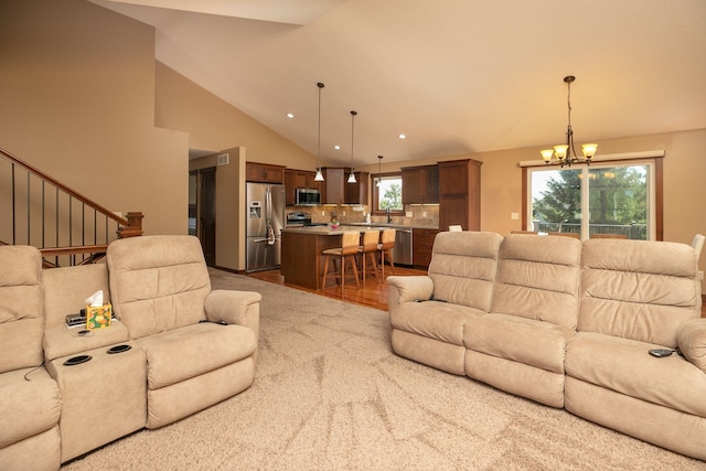 living room with wood-type flooring, sink, lofted ceiling, and a chandelier