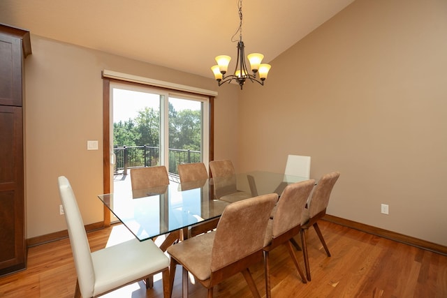 dining room with a notable chandelier, light wood-type flooring, and vaulted ceiling