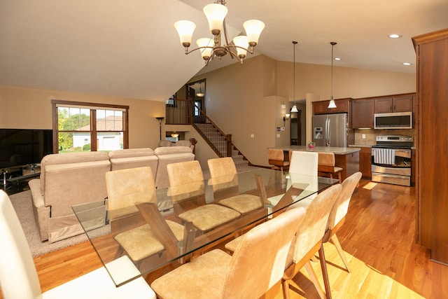 dining room with light wood-type flooring, lofted ceiling, and a chandelier