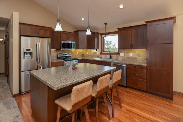 kitchen with a center island, sink, lofted ceiling, light hardwood / wood-style flooring, and stainless steel appliances