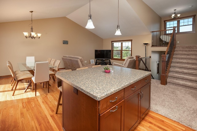 kitchen with hanging light fixtures, lofted ceiling, an inviting chandelier, and light hardwood / wood-style flooring