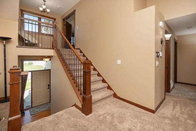 stairs with a healthy amount of sunlight, carpet flooring, and a notable chandelier