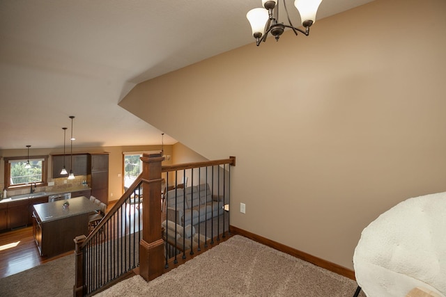 stairway featuring a chandelier, carpet flooring, and sink