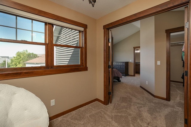 corridor featuring vaulted ceiling and light colored carpet